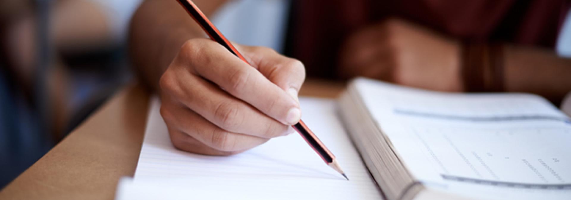 Closeup shot of a young man writing on a note pad