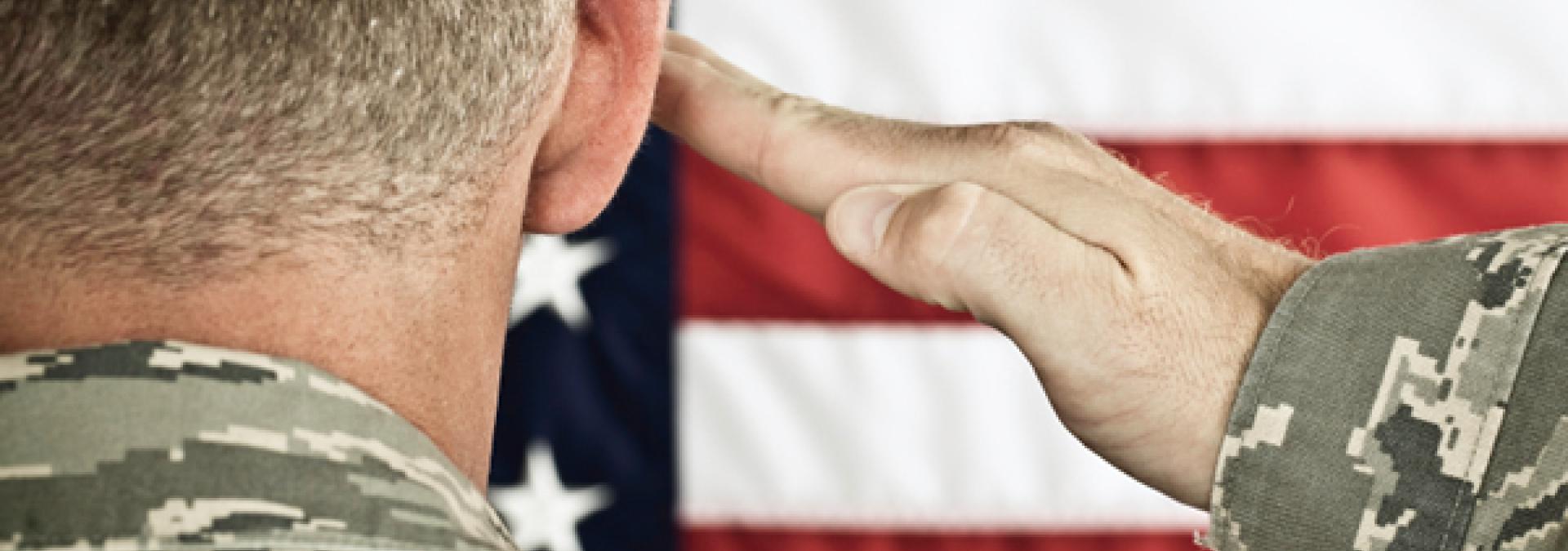 Military soldier saluting an American flag